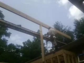 Carpenter setting a ridge beam over a new addition frame — Ice Dam Removal by Roofing Brothers in Lyndon