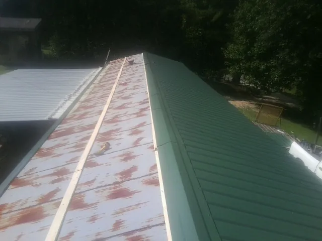 Old rusted panels beside newly installed green metal roofing — Wind Damage Roof Repair by Roofing Brothers in Lyndon