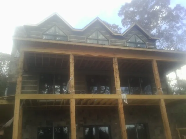 Dormers and porch framing on a large log home under construction — Roof Coating work by our crew in Lyndon