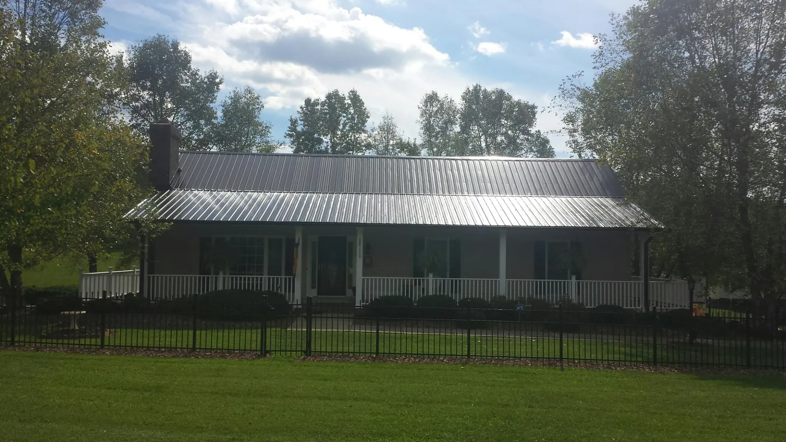 Gray metal roof on a brick ranch with a full width front porch — Gutter Guard Installation work by our crew in Lyndon