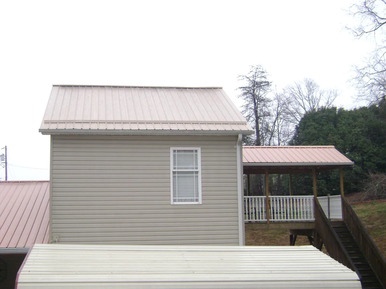 Tan metal roofs on a two story addition and attached porch, from a Roof Replacement job in Lyndon